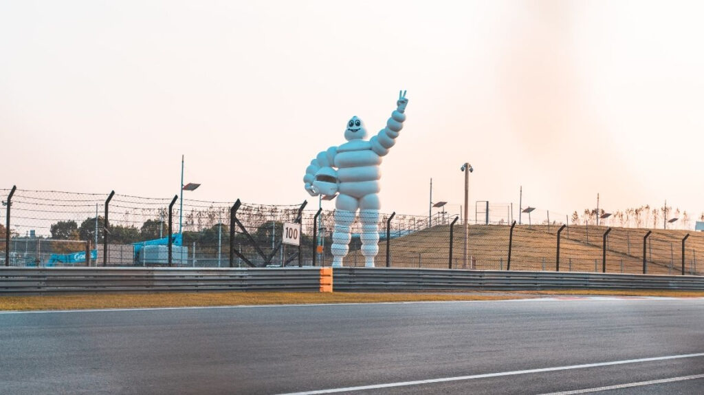 Un Bibendum en train de faire le signe peace au bord d'une route