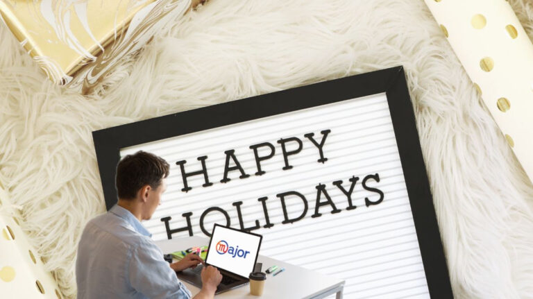 Un homme en train de travailler devant un panneau "Happy Holidays"