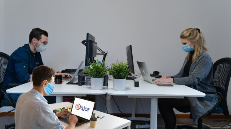 Deux hommes et une femme travaillent à leur bureau avec un masque