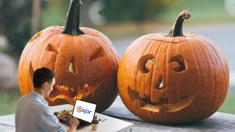Un homme travaillant sur un ordinateur devant deux citrouilles sculptées pour Halloween