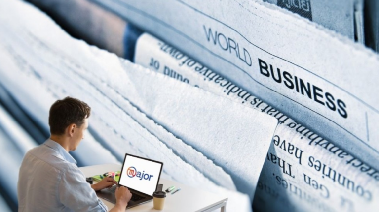 Un homme sur son ordinateur devant une photo avec des journaux business