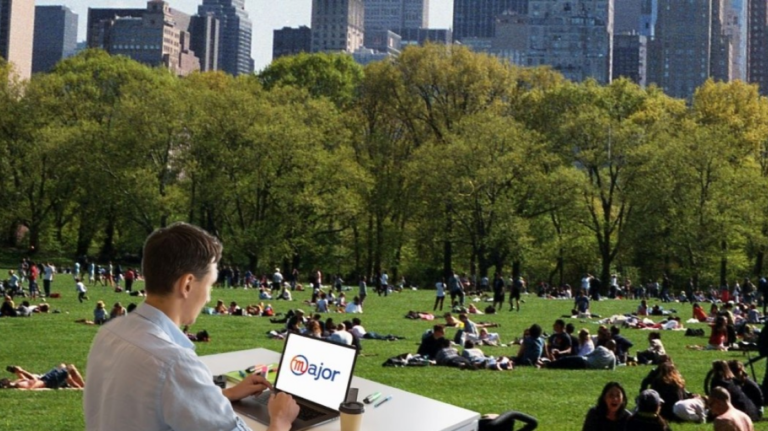 Un homme sur son ordinateur devant une photo de Central Park à New York