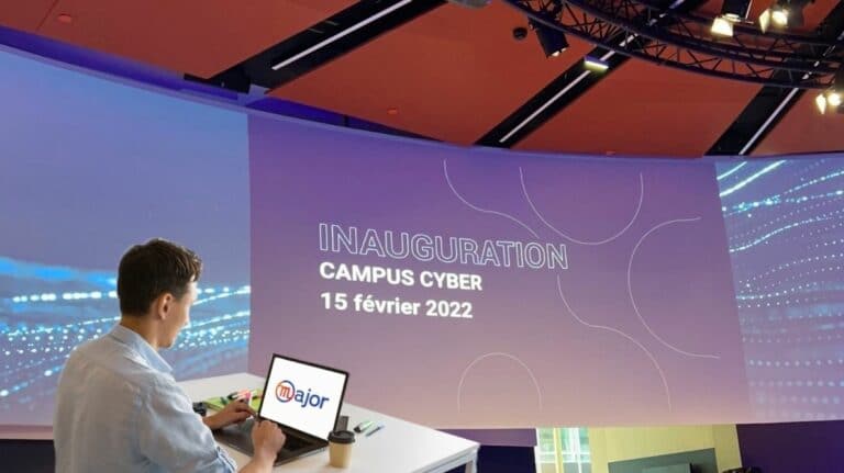Un homme en train de travailler devant un panneau inaugurant le campus cyber de La Défense