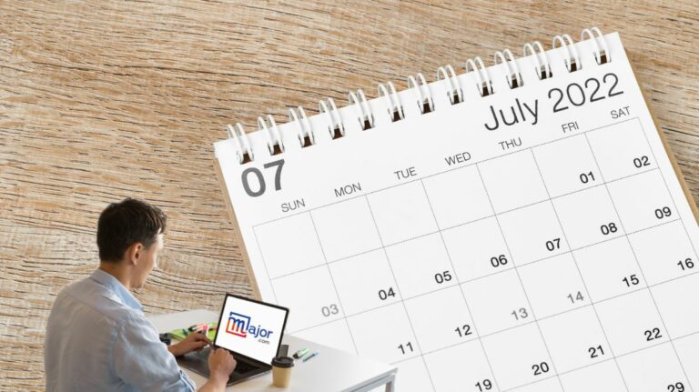 Un homme travaillant sur un ordinateur devant un calendrier du mois de juillet