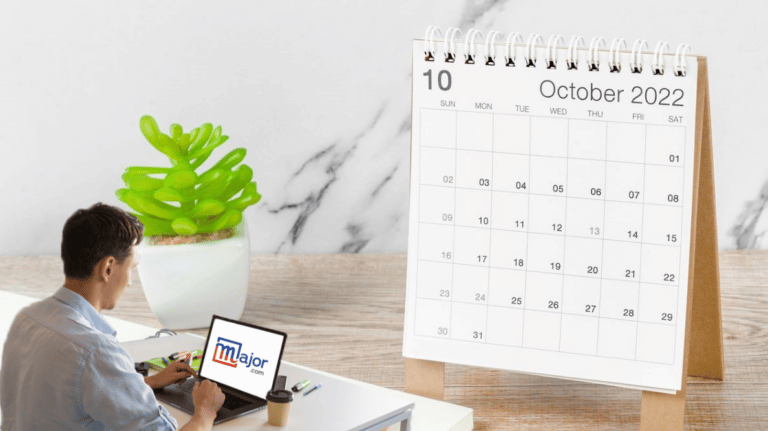 Un homme travaillant sur un ordinateur devant un calendrier du mois d'octobre