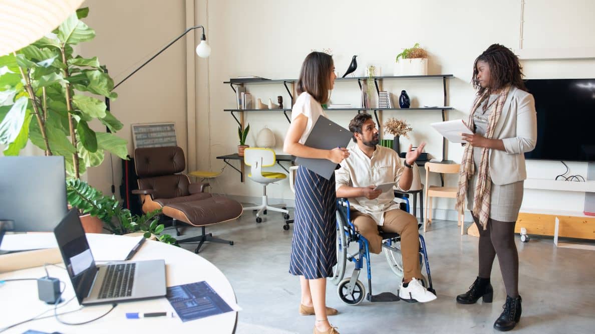 Trois personnes dont un homme en fauteuil roulant sur leur lieu de travail