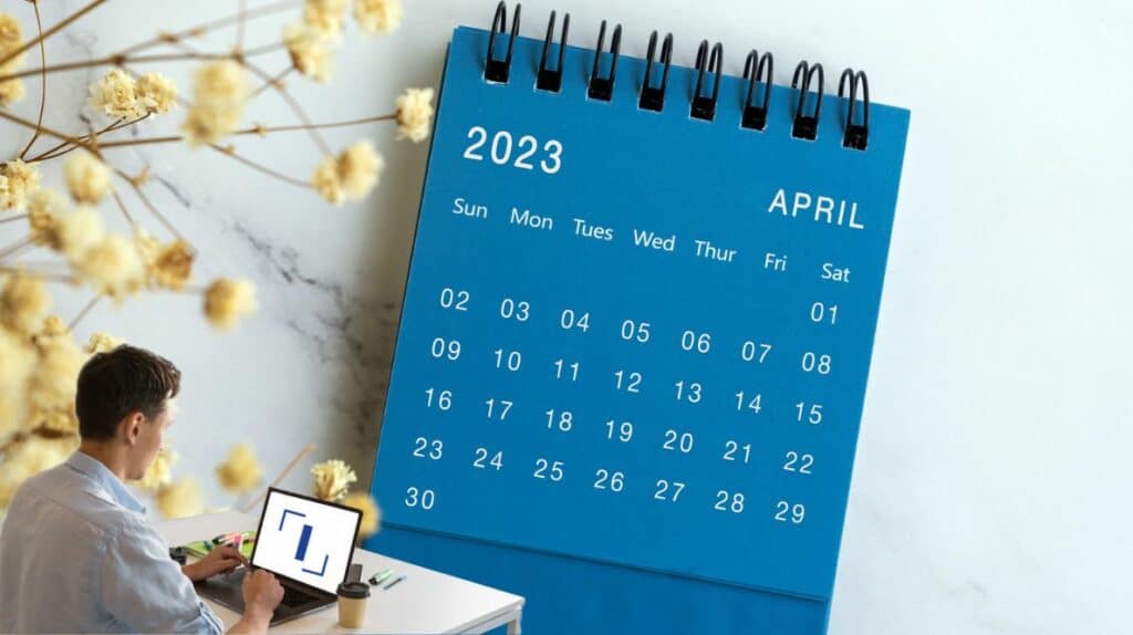 Un homme travaillant sur son ordinateur devant un calendrier du mois d'avril 2023