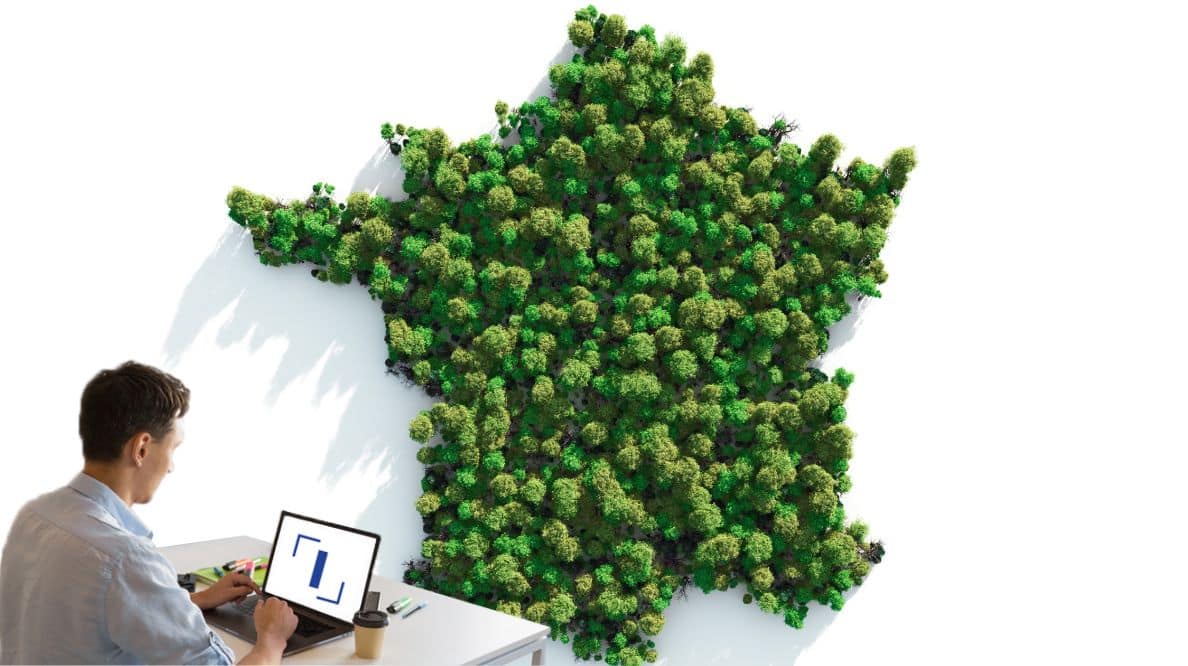 Un homme travaillant sur son ordinateur devant une carte de France faite d'arbres