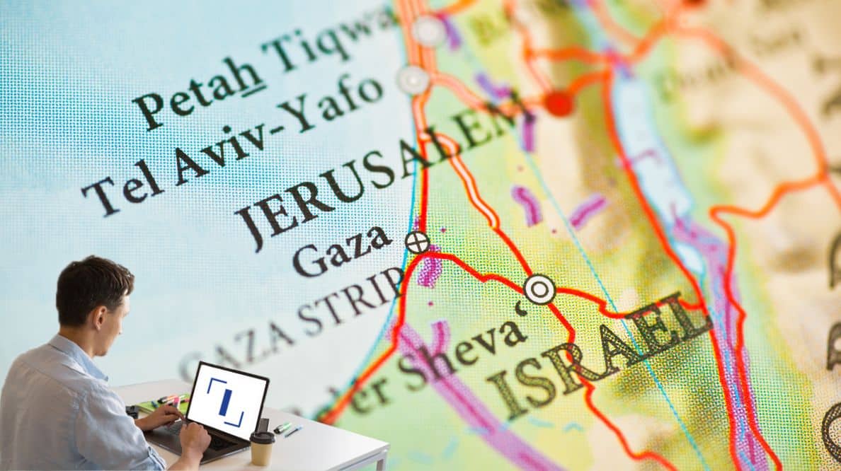 Un homme travaillant sur son ordinateur devant une carte d'Israël et de la Palestine