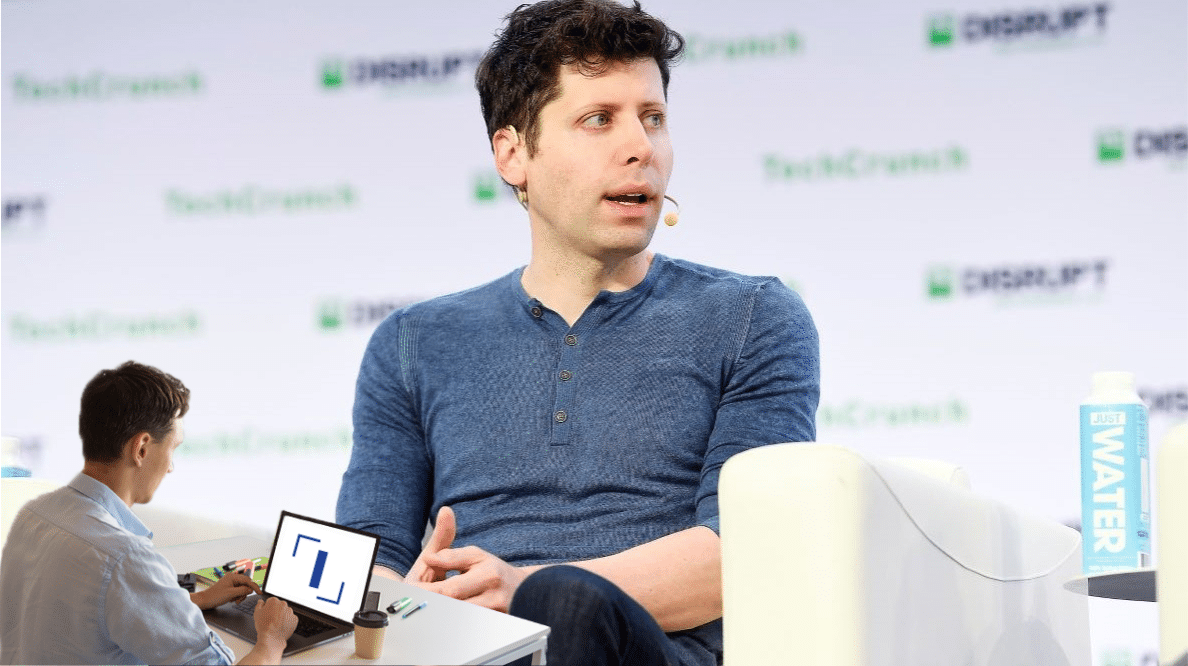 Un homme travaillant sur son ordinateur devant une photo du fondateur d'OpenAI, Sam Altman